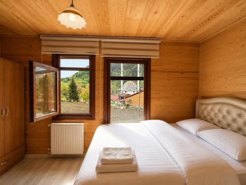 a bedroom with a large white bed with windows at CERRAHPAŞA SUİTE HOTEL in Uzungöl