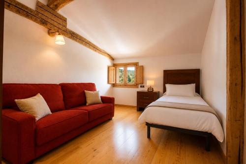 a bedroom with a red couch and a bed at El Palacito de Villoslada in Villoslada de Cameros