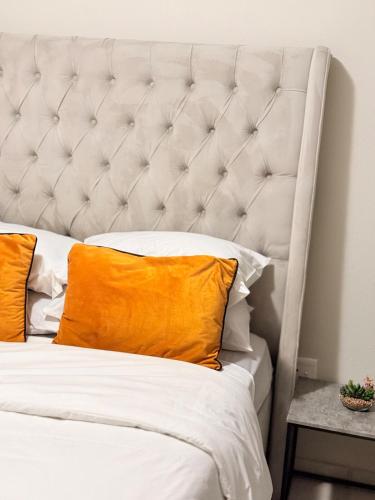 a white bed with an orange pillow on it at Kilimanjaro in Alberton