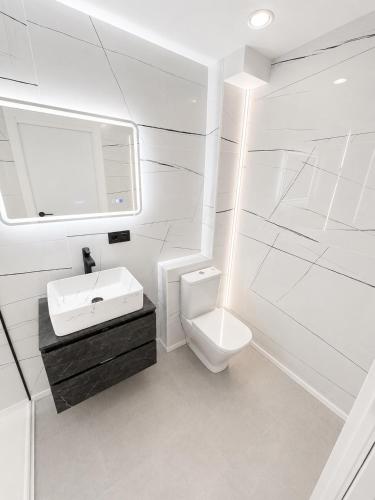 a white bathroom with a sink and a toilet at ApartamentosCRP in Almería