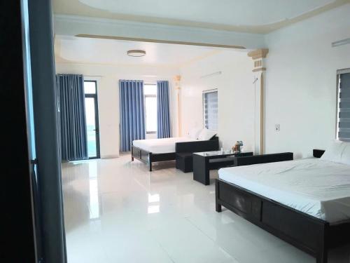 a room with two beds and a living room with a couch at PHƯƠNG LƯU Hotel in Văn Lâm