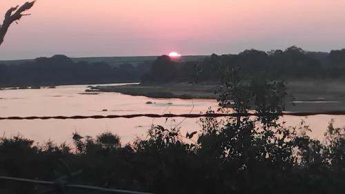 a sunset over a river with the sun setting in the background at Marloth Park, Kruger safari house - solar in Marloth Park