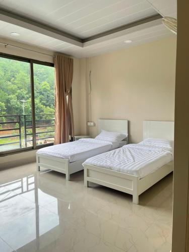 two beds in a room with a balcony at Hotel Paradise in Neihdawn