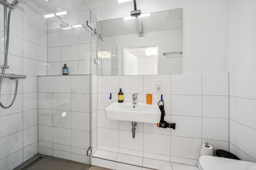 a white bathroom with a sink and a shower at Arbio I Cube Studios & Apartments St Pauli in Hamburg