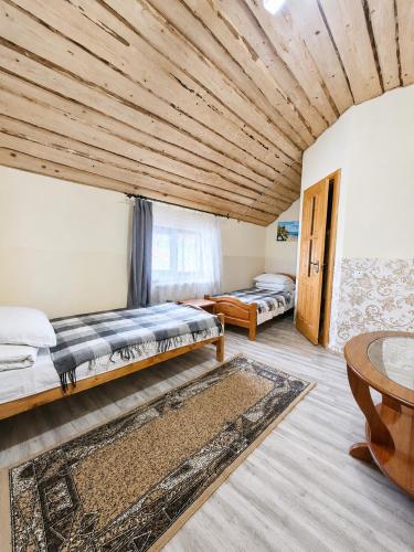 a room with two beds and a table in it at Guest House Mandrivnyi Rooms&Apartments in Yasinya