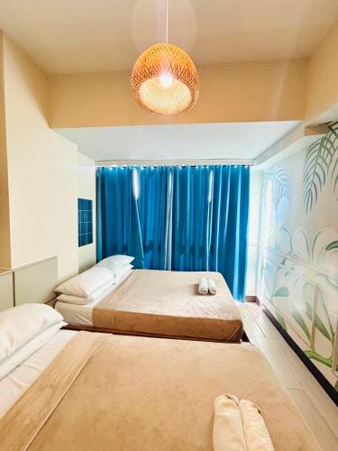 a bedroom with two beds and a blue curtain at Mactan Newtown Condo Rentals in Punta Engaño