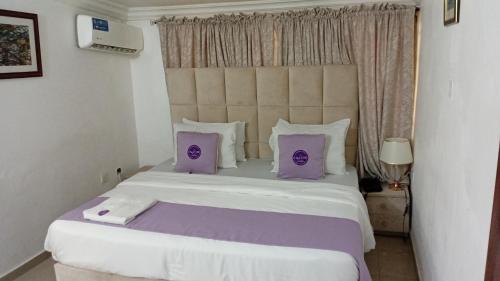 a bedroom with a large bed with purple pillows at D'Mayor Suites, Gwarinpa in Gwarinpa