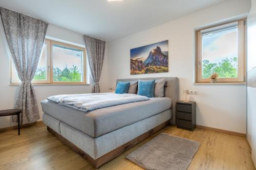 a bedroom with a bed and two windows at FeWo Iller im Allgäu in Sonthofen