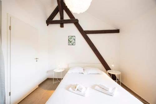 a bedroom with a white bed and wooden beams at L'évasion - duplex in Zillisheim