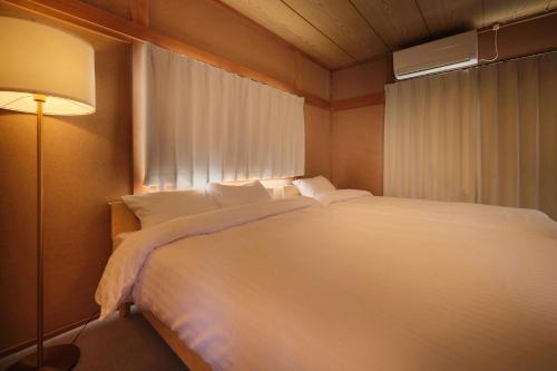 a bedroom with a large white bed with a window at Villa Vino in Fuefuki