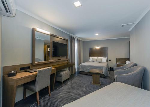 a hotel room with a bed and a desk and a mirror at Bankstown Motel 10 in Bankstown