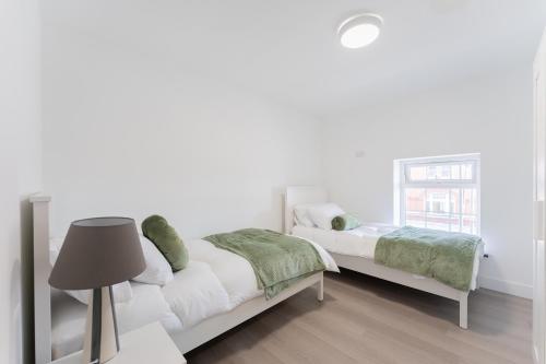 a white bedroom with two beds and a lamp at 4 Bedroom modern apartment in Birkenhead