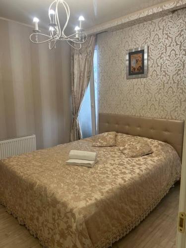 a bedroom with a large bed with a chandelier at Classic Contemporary Apartament in Chişinău
