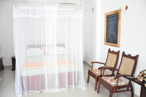 a bedroom with a bed and two chairs at Villa Gaetano Unawatuna in Unawatuna