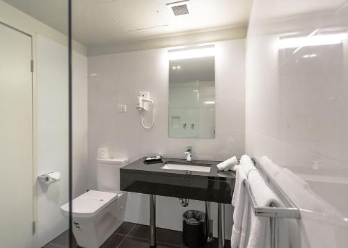 ein weißes Bad mit einem Waschbecken und einem WC in der Unterkunft Bankstown Motel 10 in Bankstown