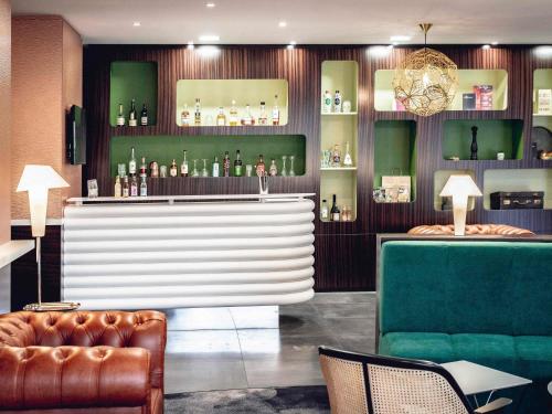 a bar with a couch and a chair in a room at Mercure Belfort Centre in Belfort