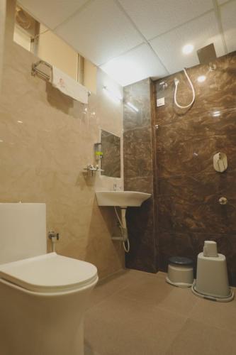 a bathroom with a toilet and a sink and a shower at Hotel Ayodhya Inn in Lokāpur