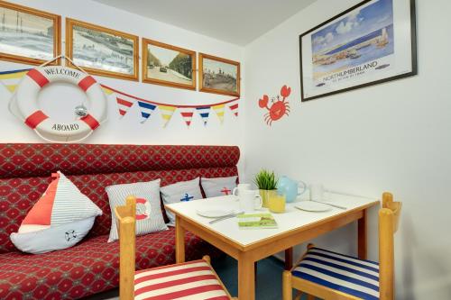a living room with a red couch and a table at The Hides in Seahouses
