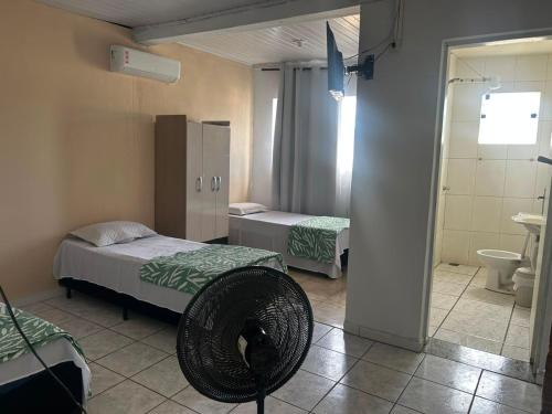 a room with two beds and a fan in it at pousada irmãs in Pindamonhangaba