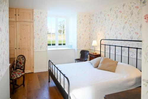 a bedroom with a bed and a chair and a window at Château de Saint Clair in Saint-Clair-sur-lʼElle