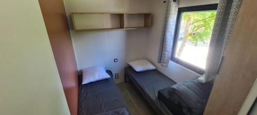 a small room with two beds and a window at Camping 3 étoiles - Piscine - ccbgbi0 in Lavelanet