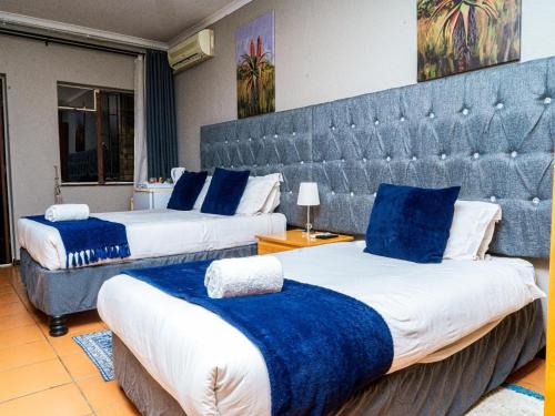 a hotel room with two beds with blue blankets at Emoyeni Guest House in Nelspruit