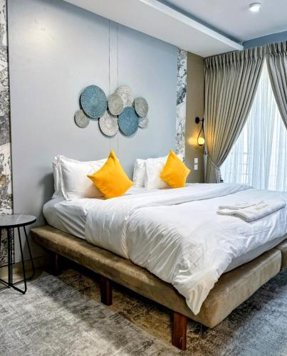 a bedroom with a large bed with yellow pillows at Habitat Service Apartment in Ilado