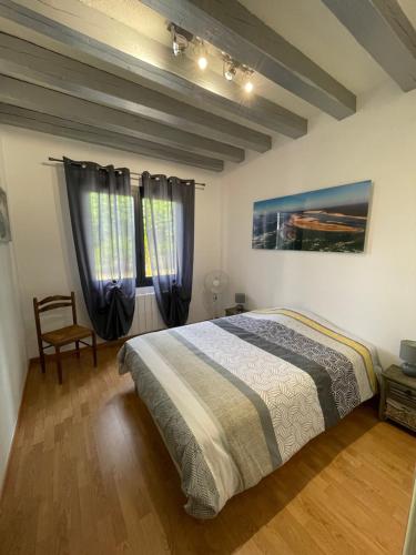 a bedroom with a bed and a chair and two windows at Gîte chez PAT in Ychoux