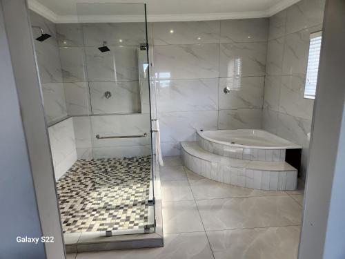 a white bathroom with a shower and a tub at Pado B & B in Gqeberha