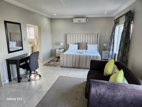 a bedroom with a bed and a desk and a couch at Pado B & B in Gqeberha