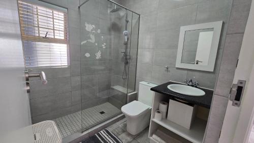 a bathroom with a shower and a toilet and a sink at La Palma villas 6 in Mossel Bay