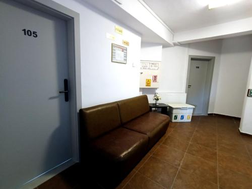Ein Wartezimmer mit einer braunen Couch vor einer Tür in der Unterkunft Hotel Liliacul in Cluj-Napoca