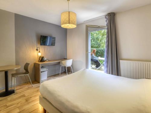 a hotel room with a bed and a desk and a window at Aparthotel Adagio Access Saint Nazaire in Saint-Nazaire