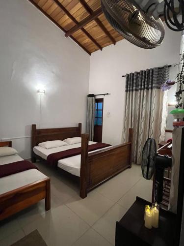 a bedroom with two beds and a desk in a room at Eightyseven guest and restaurant in Badulla