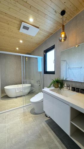 a bathroom with a tub and a toilet and a sink at 根本家民宿 in Dayi