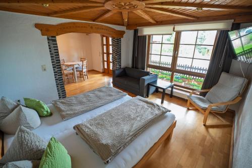 a bedroom with two beds and a chair and a table at Mettenberger Hof - Pension in Grafenhausen