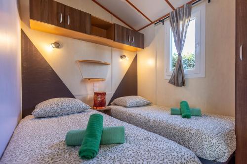 two beds in a room with green pillows at Le Chalet 67, vue Lac Guerlédan & Accès Direct à l'Eau in Caurel