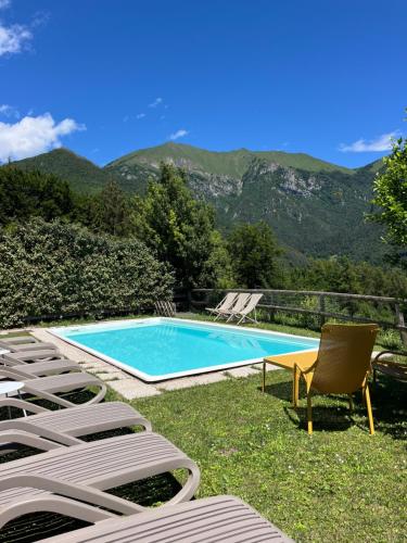 a swimming pool with chairs and a table and a chair at Casa Europa in Ledro