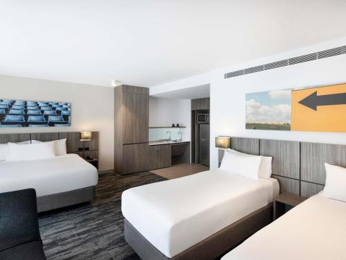 a hotel room with two beds and a desk at Mercure Sydney Blacktown in Blacktown