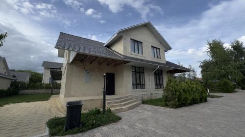 a small white house with a black door at Коттедж в Азиа Палас in Chon-Sary-Oy