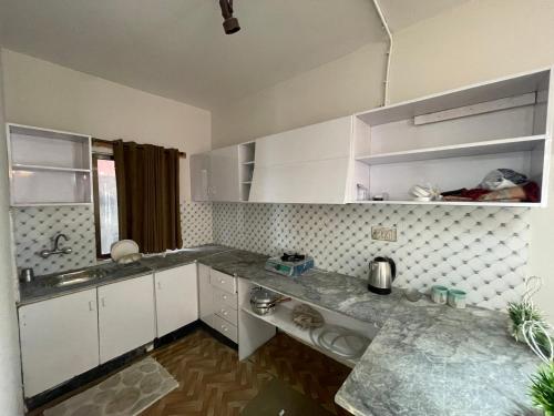 a kitchen with white cabinets and a counter top at Hillcrest Terraces Bhurban in Rāwāt