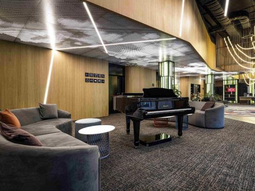 a living room with a piano and couches at ibis Almaty Jetisu in Almaty