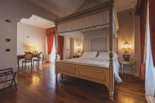 a bedroom with a canopy bed and a dining room at Hotel Villa Il Patriarca in Chiusi