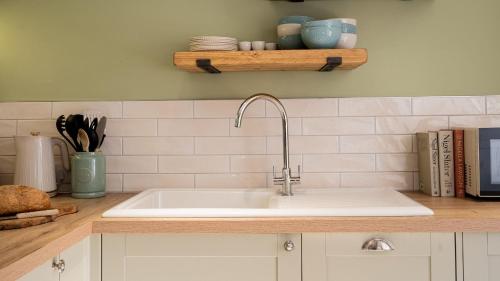 a kitchen counter with a white sink and books at Gwyndy in Beaumaris