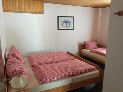 two beds in a room with red sheets at Haus Serena in Sonnenalpe Nassfeld