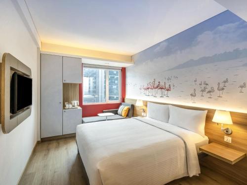 a bedroom with a large bed and a painting on the wall at ibis Mumbai Vikhroli - An Accor Brand in Mumbai