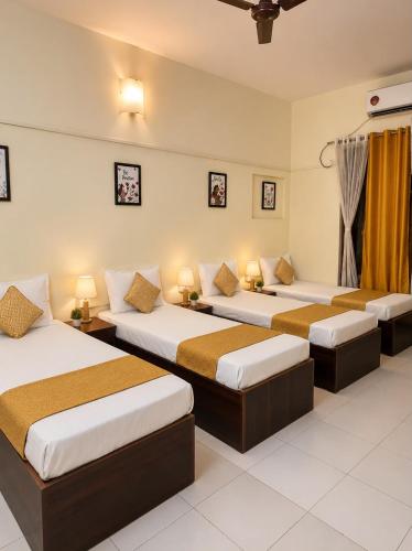 a room with three beds and two lamps at Elite Stays Viman Nagar in Pune