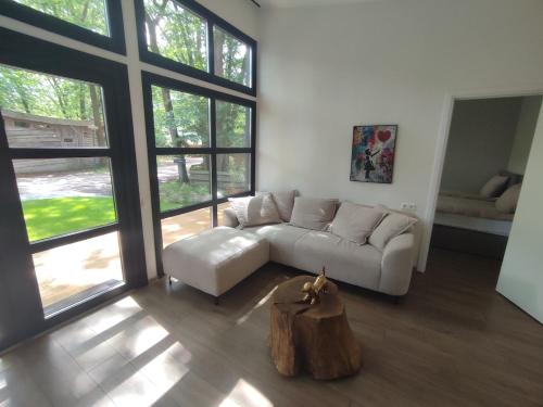 a living room with a white couch and a tree stump in the middle at Luxe chalet midden in de natuur in Rijen