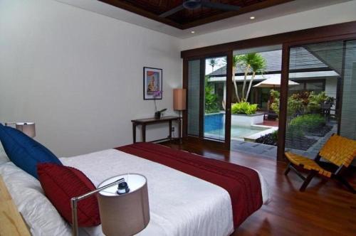 a bedroom with a bed and a sliding glass door at Villa Kejora 10 in Sanur