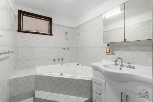 a white bathroom with a tub and a sink at The Newby in Lancelin